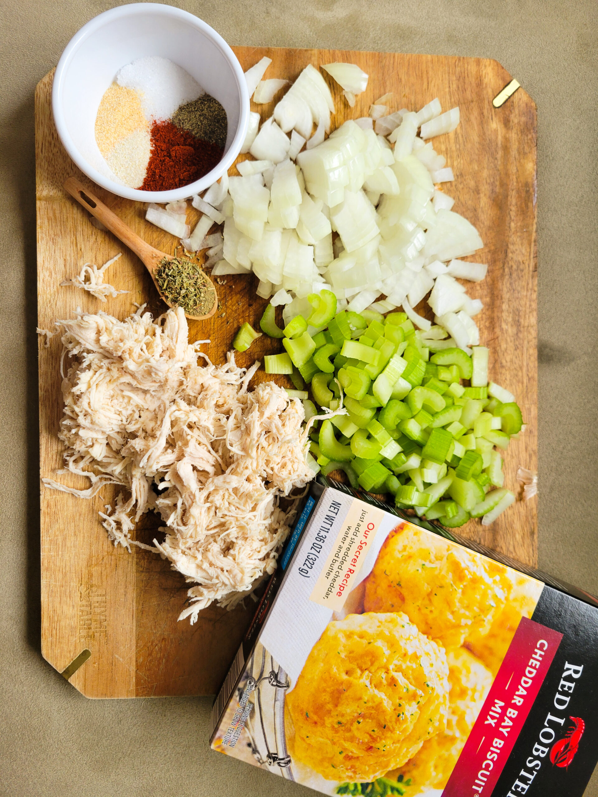 A wooden cutting board with ingredients for chicken pot pie placed on it.